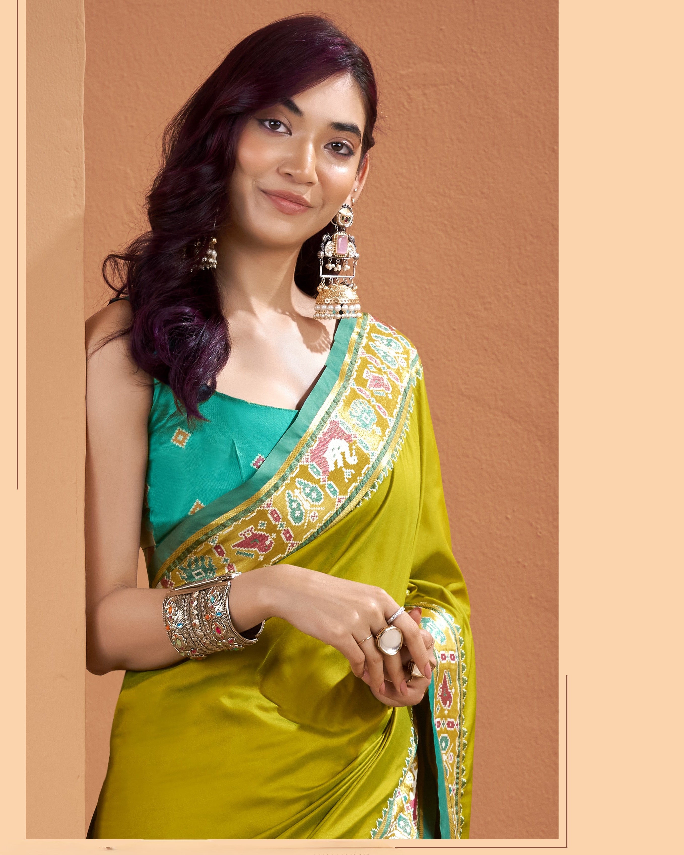 Close-up of olive yellow Patola Silk ready to wear saree with pocket showing its detailed teal, pink, cream and mustard geometric border