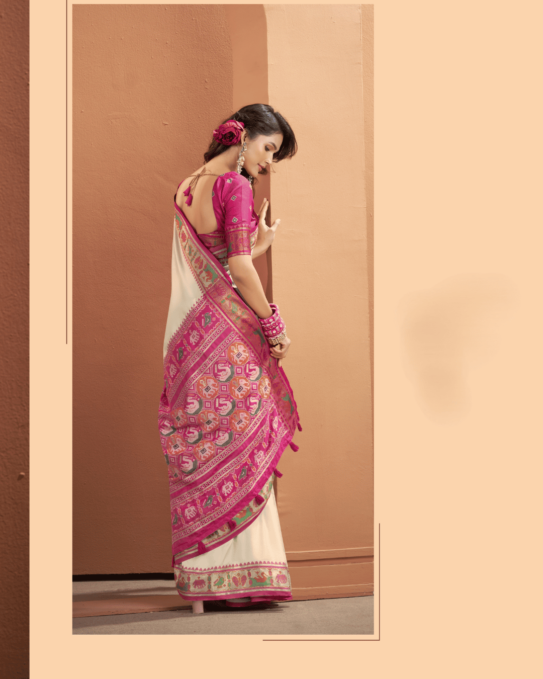 Full back portrait highlighting the statement Patola pallu framed in bold magenta pink, intricately woven with traditional geometric motifs, bird patterns in pink and green, and finished with pink tassel trim.