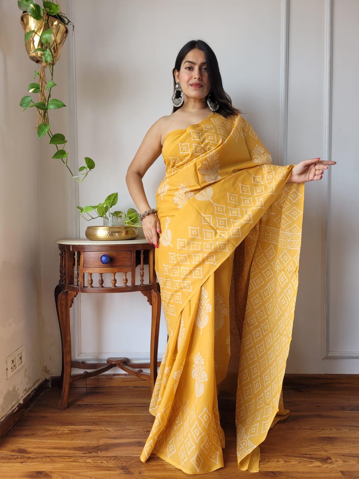 Full-length shot of a model wearing a mustard yellow Aangan Mul cotton ready to wear ppcket saree featuring white geometric diamond and floral prints.