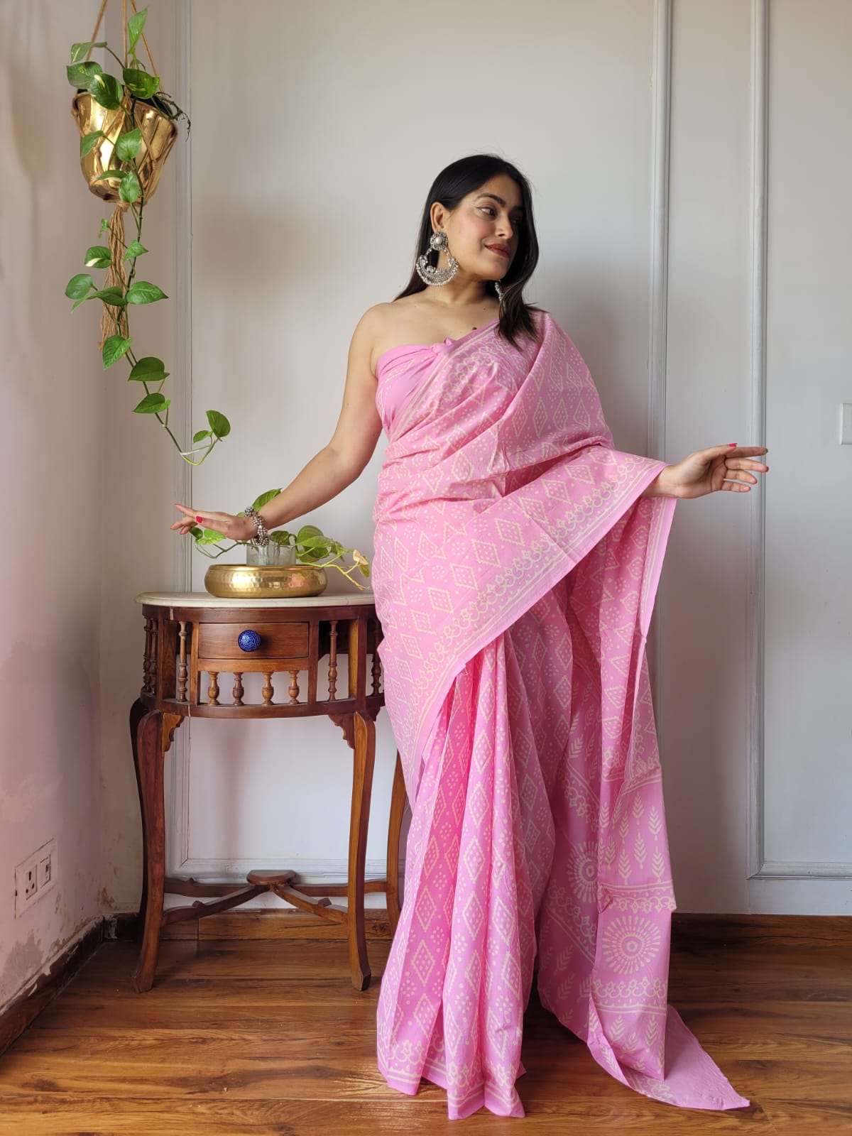 Full-length shot of a model wearing a soft pink Aangan Mul cotton ready to wear pocket saree featuring white geometric diamond prints and an ornate floral pallu.