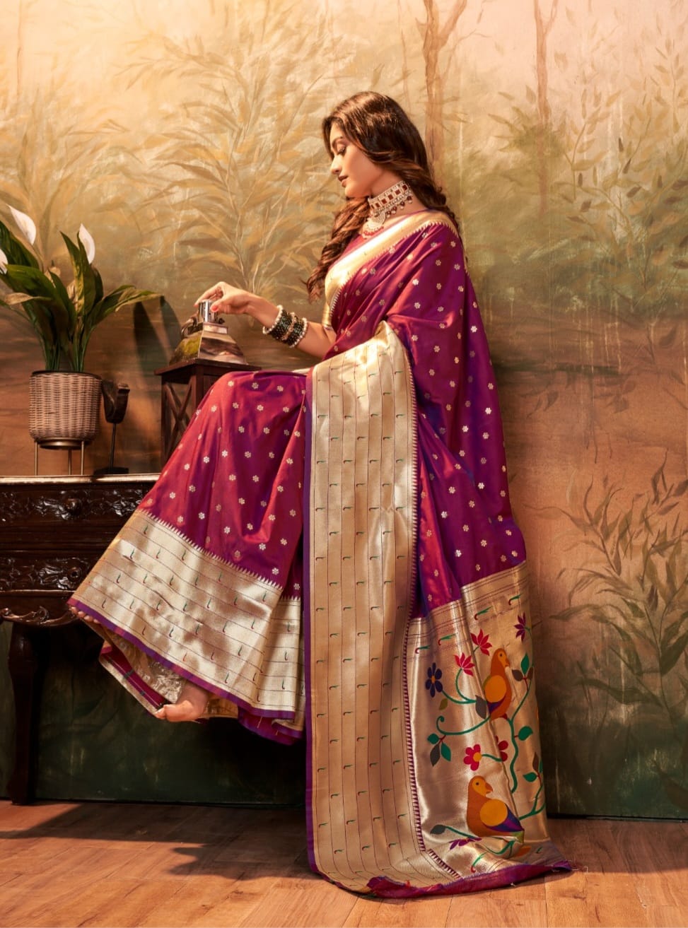 Seated profile of the royal purple Lavanya powerloom Paithani silk ready-to-wear pocket saree, featuring small ivory-gold floral motifs, a broad antique-gold lower border, and a rich pallu with colorful bird-and-floral artwork.